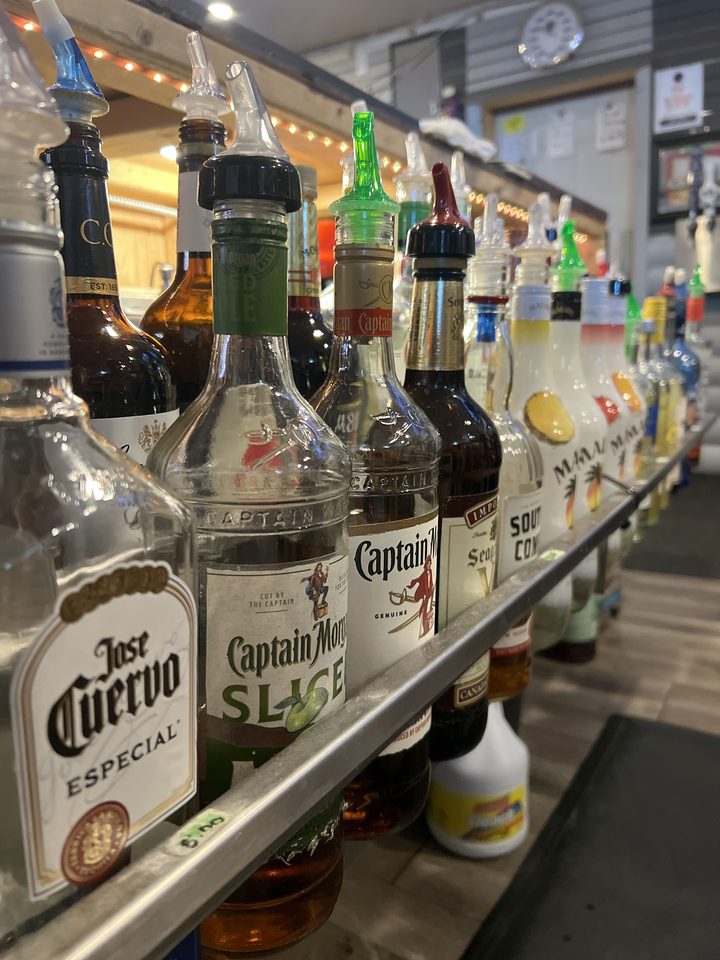 Bottles with pour spouts lined up on the bar rail at The Root Cellar